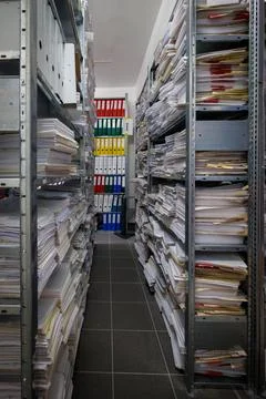 An interior view of a document archive room with metal shelving units fille.. Stock Photos