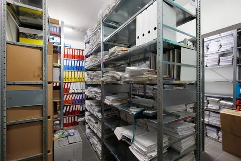 An interior view of a document archive room with metal shelving units fille.. Stock Photos
