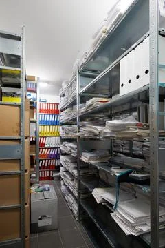 An interior view of a document archive room with metal shelving units fille.. Stock Photos
