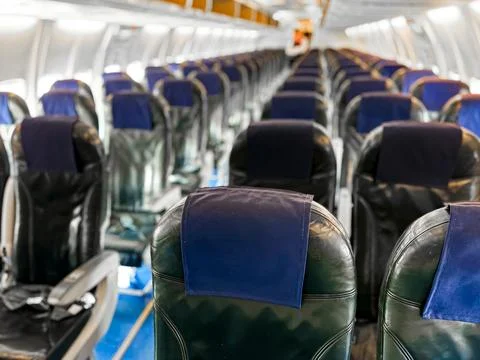 Interior view of empty airplane cabin with rows of black leather seats and blue Foto stock
