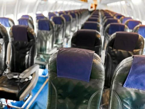 Interior view of empty airplane cabin with rows of black leather seats and blue Stock Photos