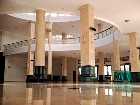 Interior view of a grand mosque with a high ceiling, marble pillars, and a .. Stock Photos