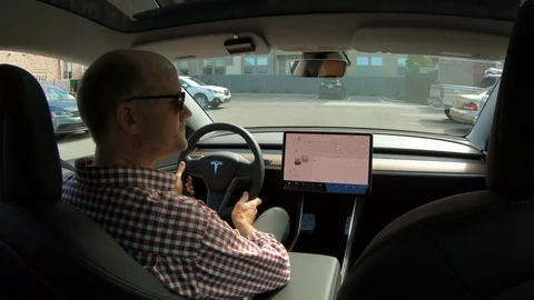 Interior view of man using Autopilot feature Autopark in a Tesla Model 3. Stock Footage 113387521