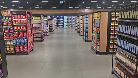 Interior view of a modern, brightly lit supermarket aisle flanked by well-stock Video stock 338259346