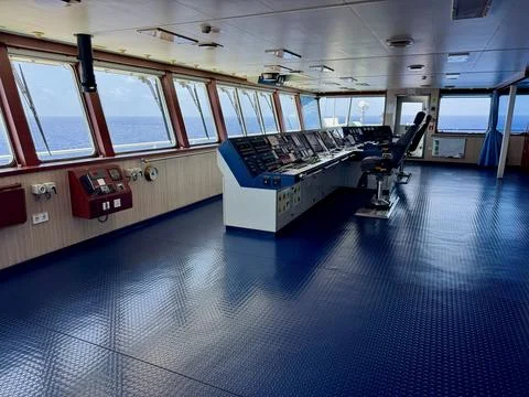 Interior view of a modern ship navigation bridge with control panels and windows Stock Photos