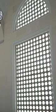 Interior view of a mosque showcasing a large arched window with a honeycomb.. Stock Photos