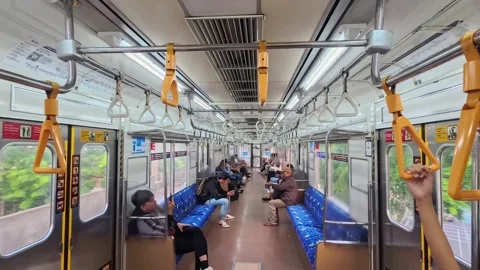 Interior view of a moving commuter train with various people sitting on train Stock Footage 315109024