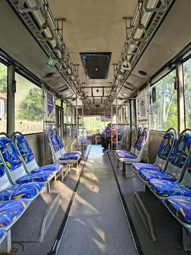 Interior view of a public bus with blue passenger seats and hanging hand grips. Stock Photos