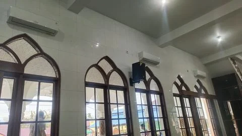 Interior view of a room with arched windows and air conditioning units. Stock Photos
