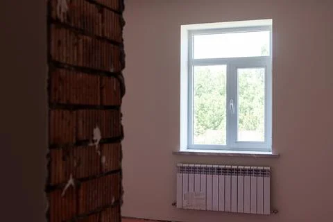 Interior view of a room featuring a large window with white frames, a radia.. Stock Photos
