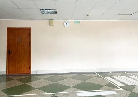 Interior view of a simple room featuring a wooden door, wall clock, and Stock Photos