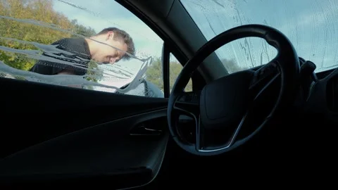 Interior view through wet windshield as attendant wipes exterior glass Stock Footage 337042013