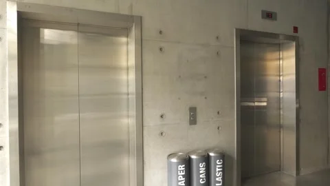 Interior view of two side-by-side elevator doors in a concrete building, one Stock Footage 323045293