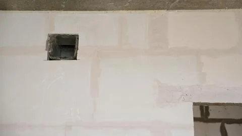 Interior wall with unfinished plasterboard, joint compound, and a square ve.. Stock Photos