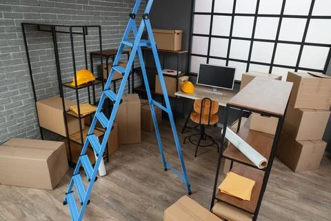 Interior of warehouse with workplace, shelf units and stepladder Stock Photos