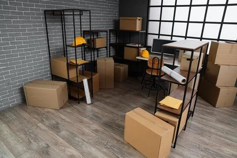 Interior of warehouse with workplace, shelf units and cardboard boxes Stock Photos