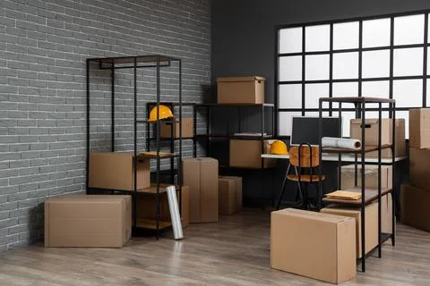 Interior of warehouse with workplace, shelf units and cardboard boxes Stock Photos