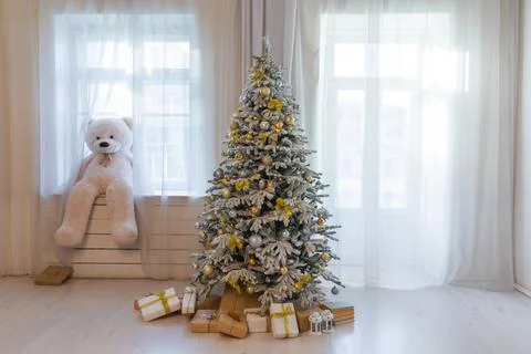 Interior of a white room with a snow-covered christmas tree with gifts Stock Photos