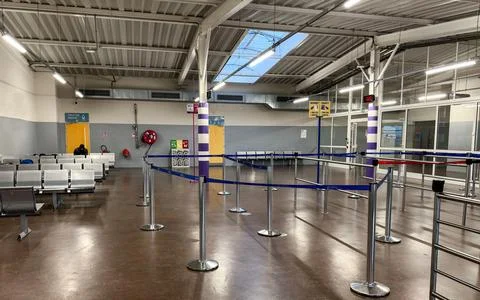 An interior, wide-angle view of a utilitarian and sparsely populated airport Stock Photos