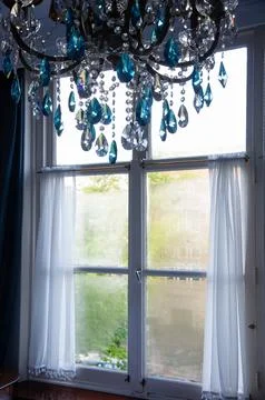 Interior of a window looking out to early morning with chandelier in front Stock Photos