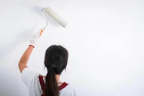 Interior working, Painter hand in white glove painting wall with paint roller Stock Photos