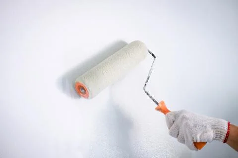 Interior working, Painter hand in white glove painting wall with paint roller Stock Photos