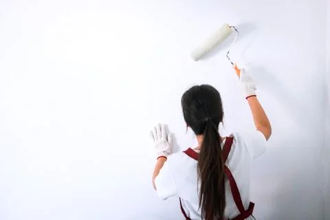 Interior working, Painter hand in white glove painting wall with paint roller Stock Photos