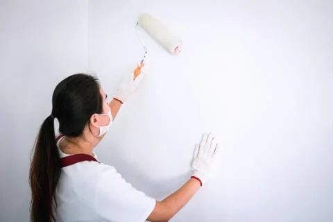 Interior working, Painter hand in white glove painting wall with paint roller Stock Photos