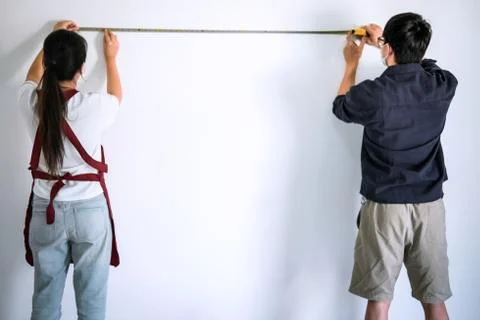Interior working, Two painter with measure tape checking wall length in room, Stock Photos