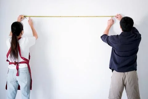 Interior working, Two painter with measure tape checking wall length in room, Stock Photos
