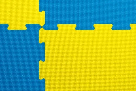 Interlocking blue and yellow foam flooring tiles inside a gym or play room Stock Photos