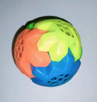 Interlocking plastic puzzle sphere toy with vibrant green, orange, and blue piec Stock Photos