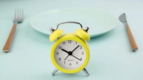 Intermittent fasting, diet, lunch time concept. Alarm clock, plate and cutlery. Stock Footage 239179292