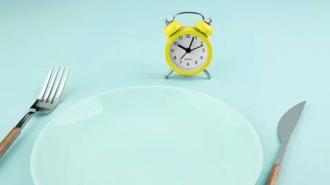 Intermittent fasting, diet, lunch time concept. Alarm clock, plate and cutlery. Stock Footage 239179294
