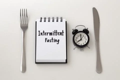 Intermittent fasting word on notepad with clock, fork and knife, weight loss  Stock Photos