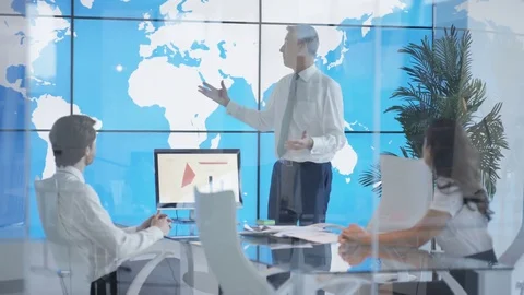 International business team in a meeting, looking at world map on video wall and Stock Footage