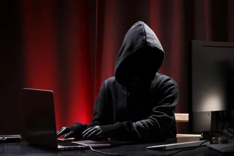 International hacker in black pullover and black mask trying to hack government Stock Photos