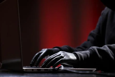 International hacker in black pullover and black mask trying to hack government Stock Photos