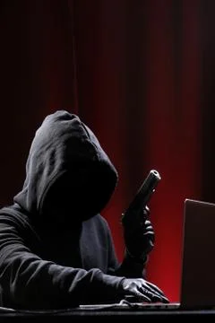 International hacker in black pullover and black mask trying to hack government Stock Photos