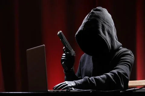 International hacker in black pullover and black mask trying to hack government Stock Photos