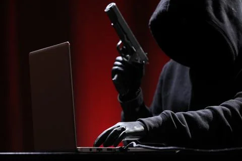 International hacker in black pullover and black mask trying to hack governme Stock Photos