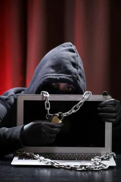 International hacker in black pullover and black mask trying to hack government Stock Photos