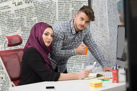 International multicultural team at work: asian muslim woman and caucasian man. Stock Photos