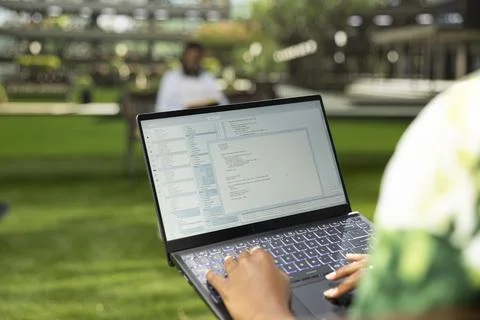 International student using laptop with coding content on campus bench Stock Photos