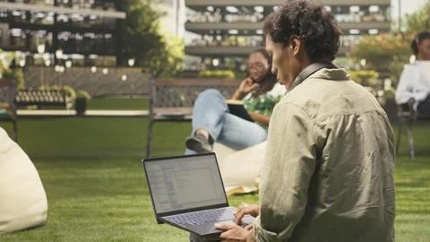 International student using laptop with coding content on campus bench Stock Photos