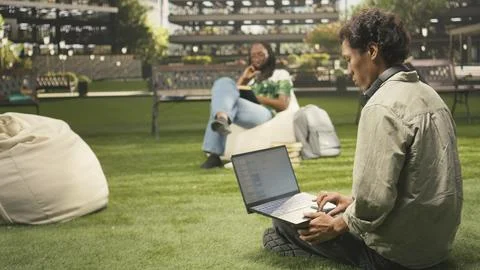 International student using laptop with coding content on campus bench Stock Photos
