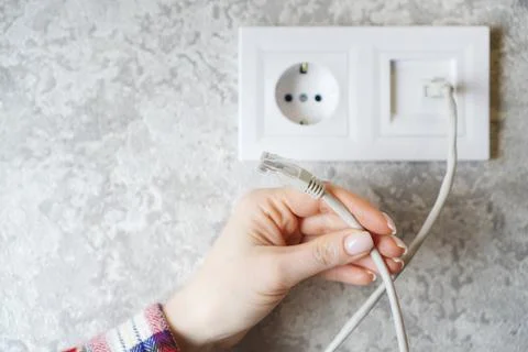 Internet cable in female hands. Network socket on the backdrop. Foto stock