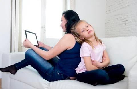 Internet network addict mother using digital tablet ignoring little sad daughter Stock Photos