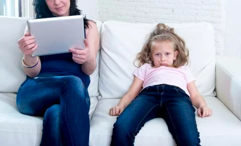 Internet network addict mother using digital tablet ignoring little sad daughter Stock Photos