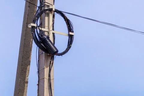 An internet or electric cable, rolled up into a ring, hangs on a pole. Stock Photos